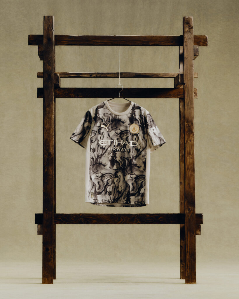 Graphic t-shirt with abstract design displayed on a wooden hanger against a neutral background. - Totalsports